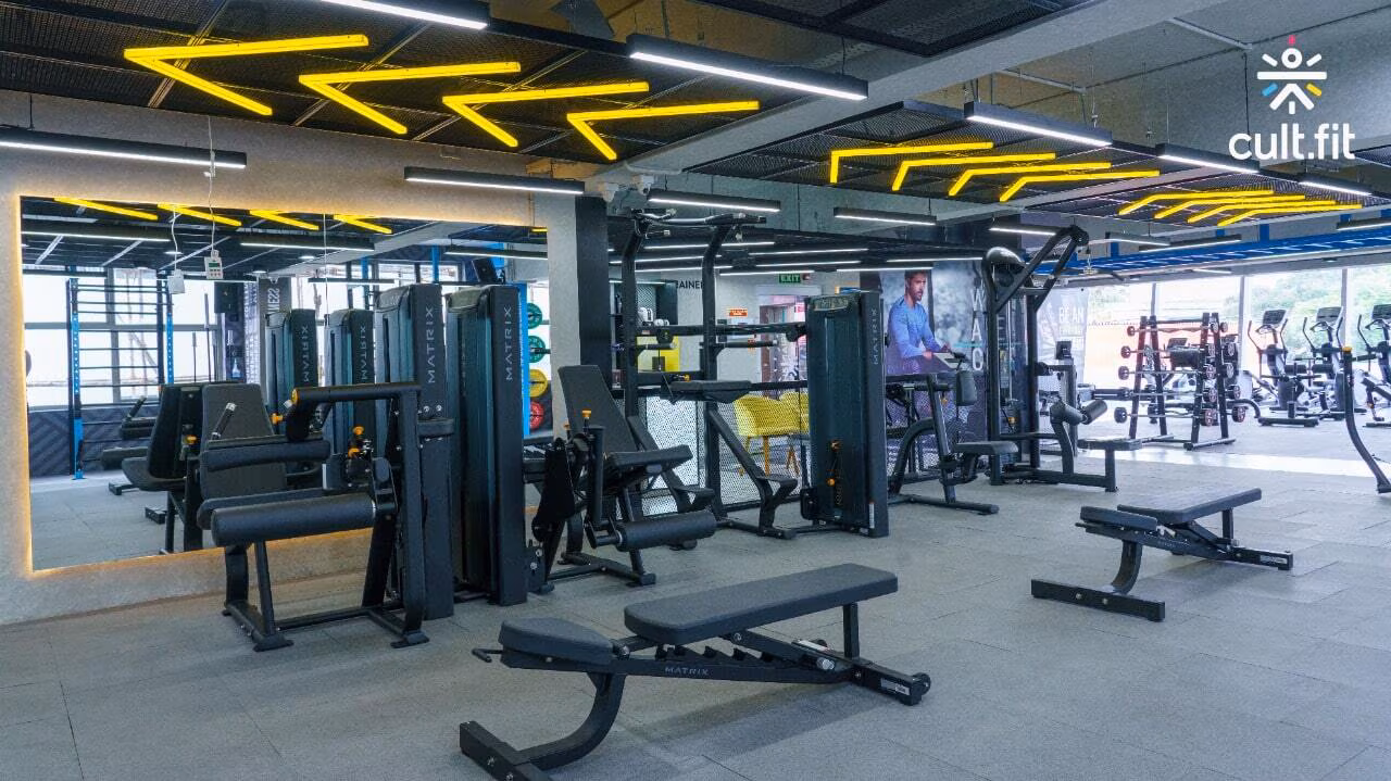Industrial-style gym interior with black equipment and neon lights.